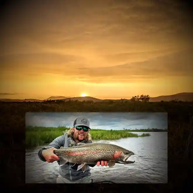 Arolik River sunset scene with fisherman holding large leopard rainbow trout on exclusive Alaska float trip